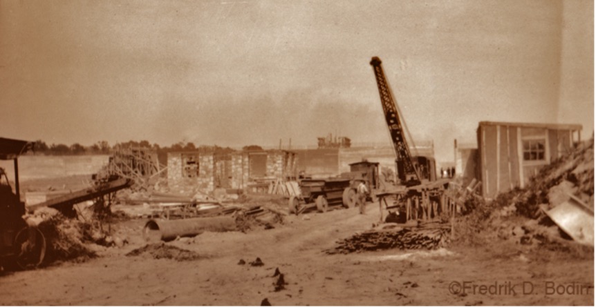 Sepia photo or construction equipment and a building.